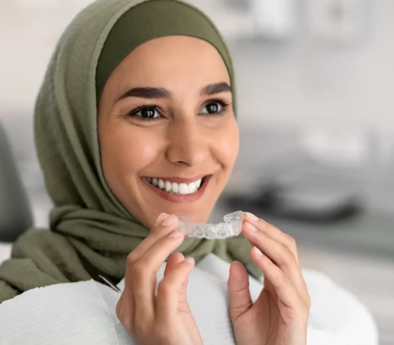 a woman wearing a green head scarf holding a clear plastic device